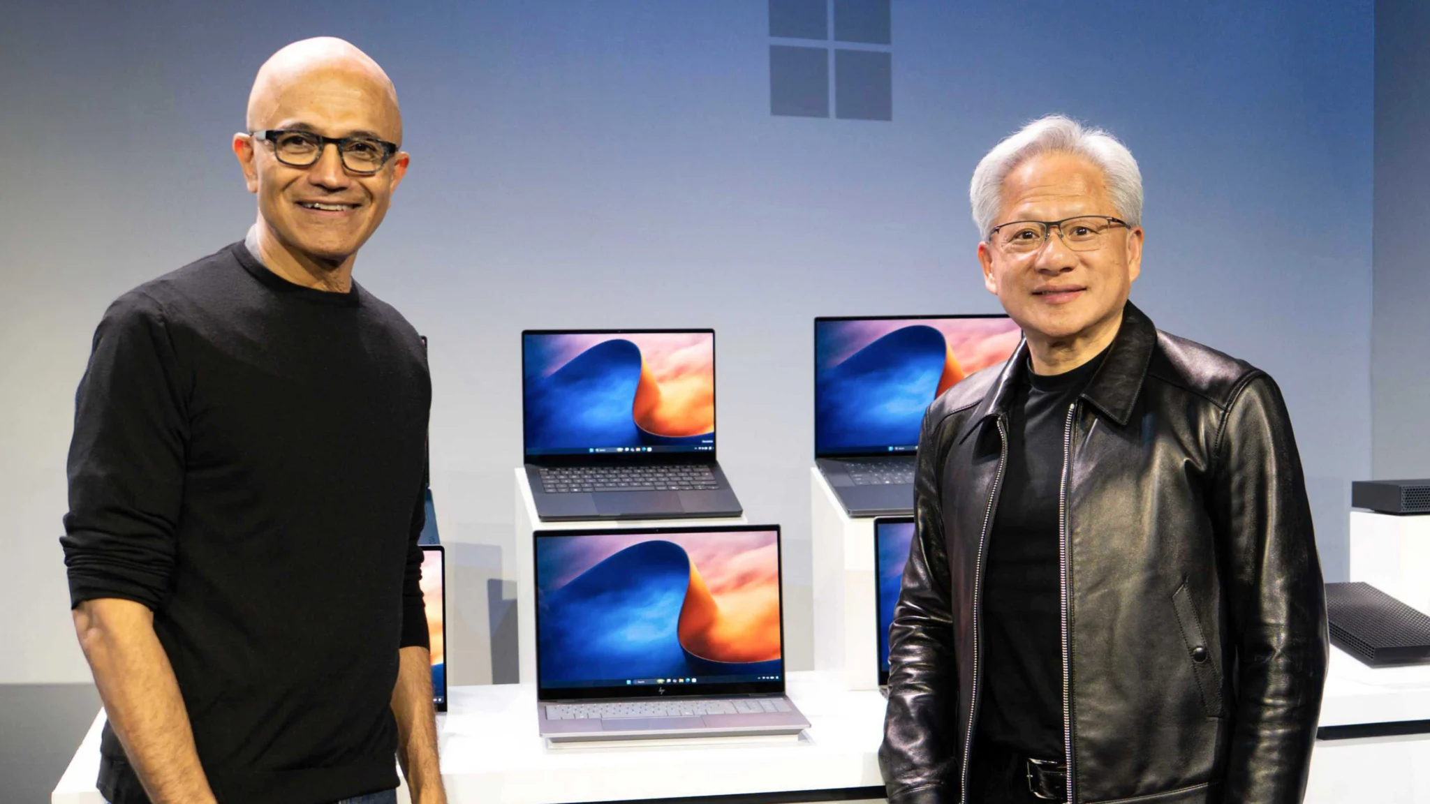 Satya Nadella and Jensen Huang beside Windows laptops at the Microsoft and NVIDIA event